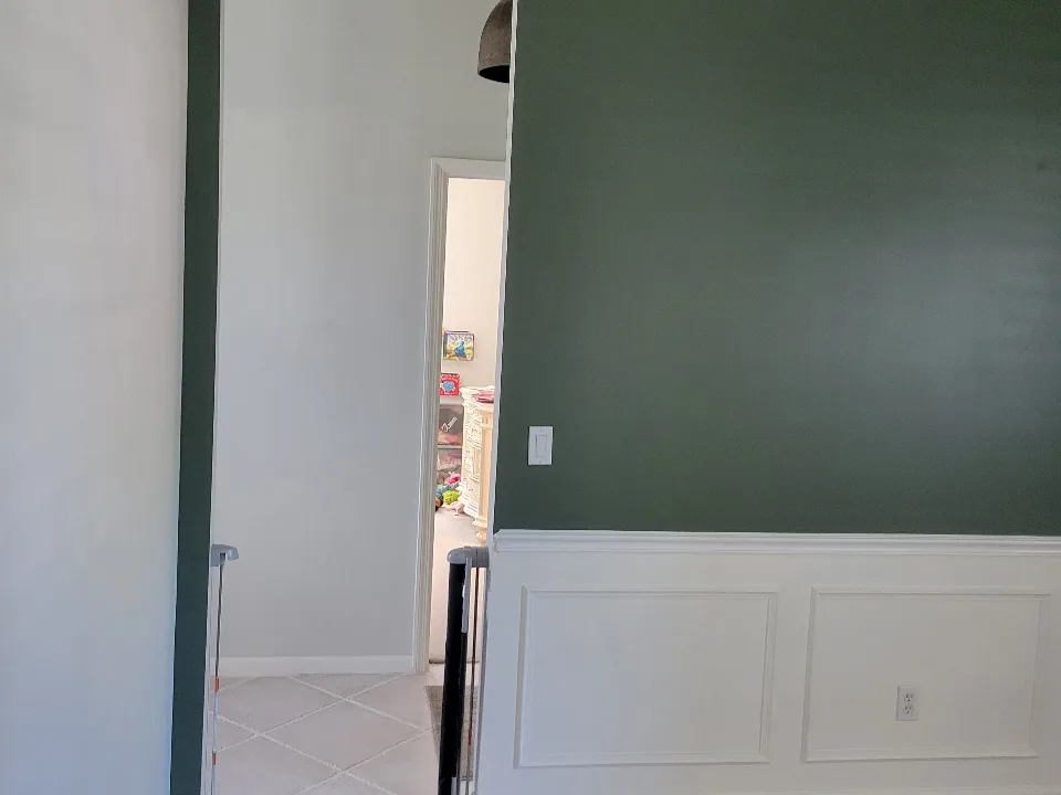 The same wall repainted in a soft sage green with the white wainscoting preserved