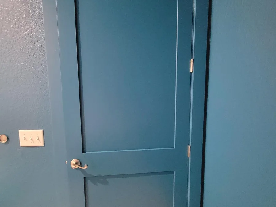The same bathroom door and surrounding wall finished in a bold peacock teal