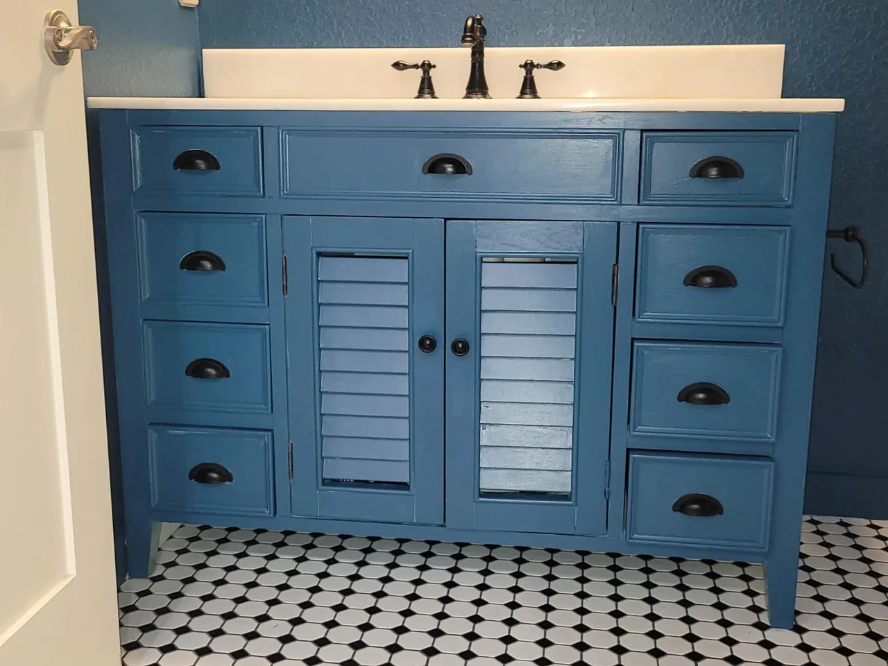 The same vanity cabinet refinished in a rich slate blue to match the newly painted walls