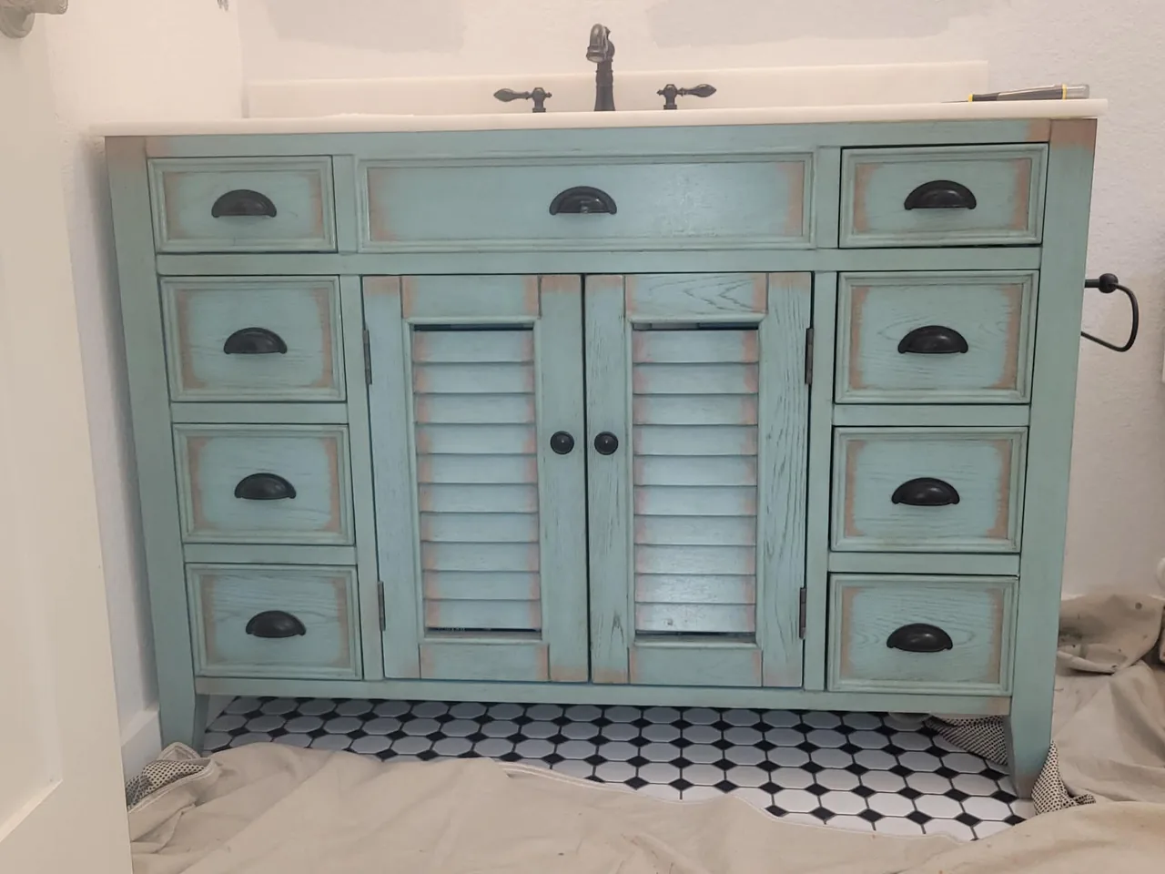 Weathered, distressed pale seafoam-blue bathroom vanity cabinet before refinishing
