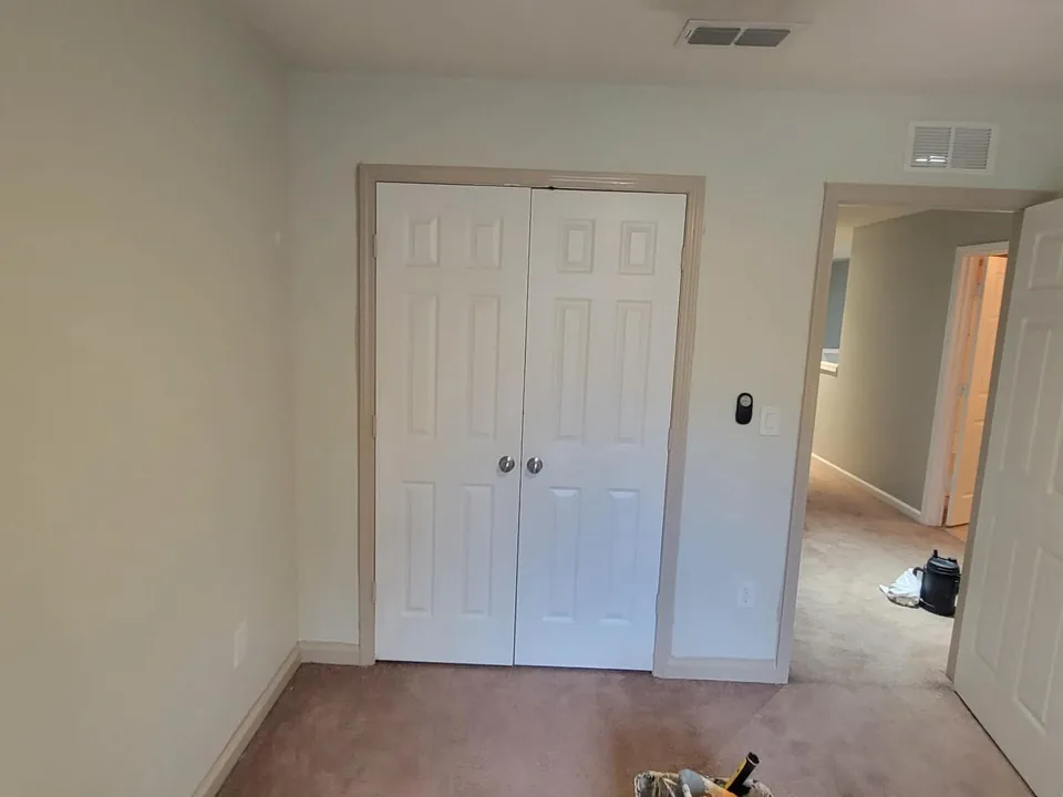 Plain beige bedroom walls and matching white closet doors before painting