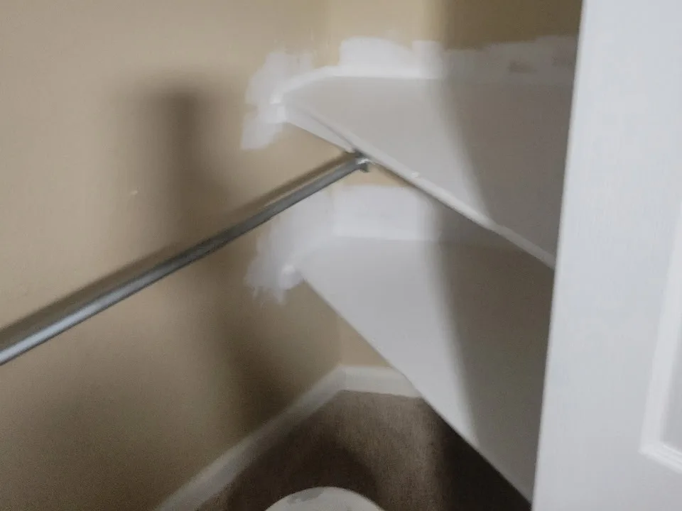 Dated tan closet interior with built-in shelving before painting