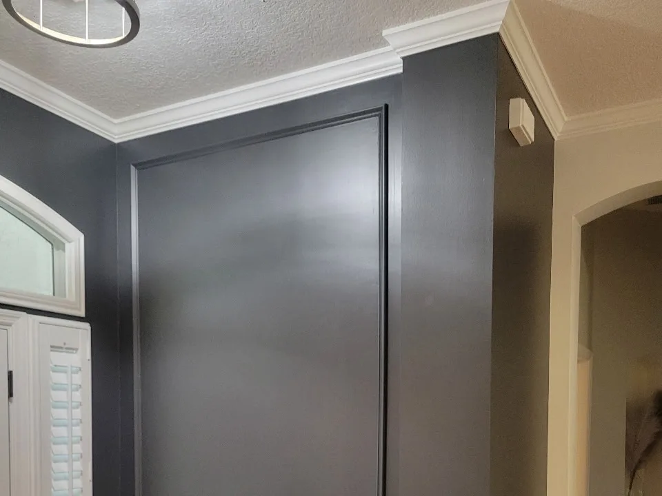 The same entryway wall paneling finished in deep charcoal with crisp white trim