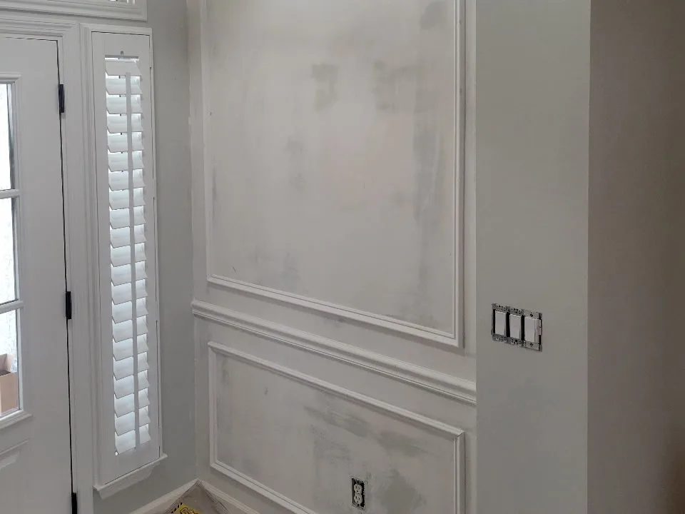 Patched and primed white board-and-batten entryway wall paneling before painting