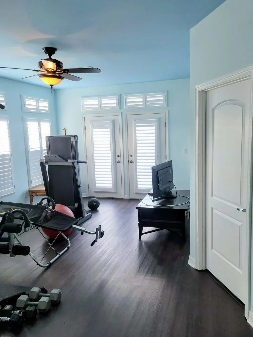 Finished home gym and flex room painted in soft sky blue with white French doors and trim by In Living Color Painters