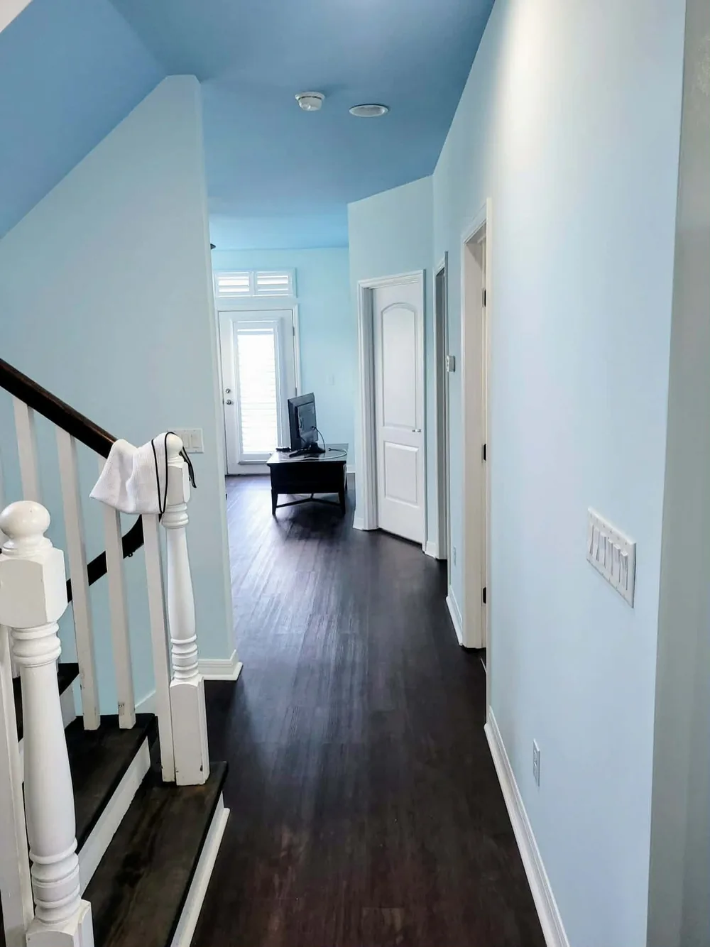 Finished hallway and stairwell painted in soft sky blue with crisp white trim and stair railing by In Living Color Painters