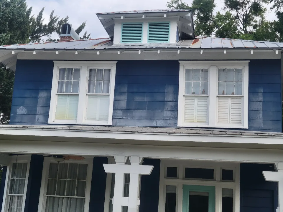 Faded, patchy blue lap siding on a historic two-story home before repainting