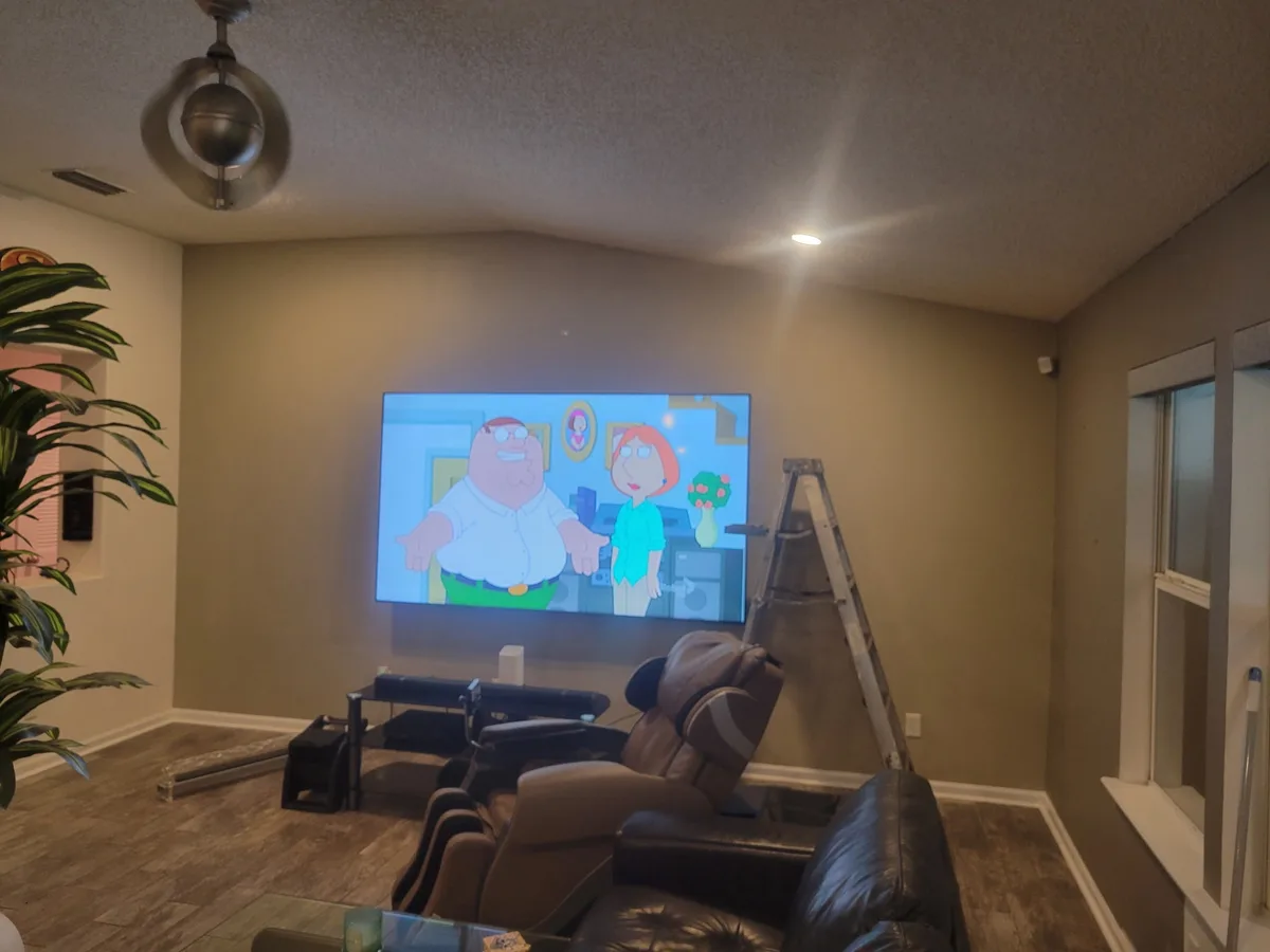 Plain olive-tan media room wall behind a wall-mounted TV before painting