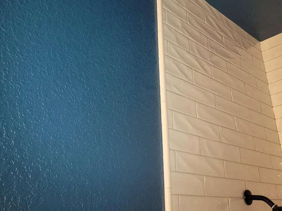 The same shower surround framed by walls and ceiling finished in a bold teal blue