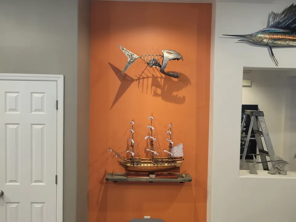 The same wall niche finished in bold burnt-orange, styled with a model ship and a metal fish sculpture